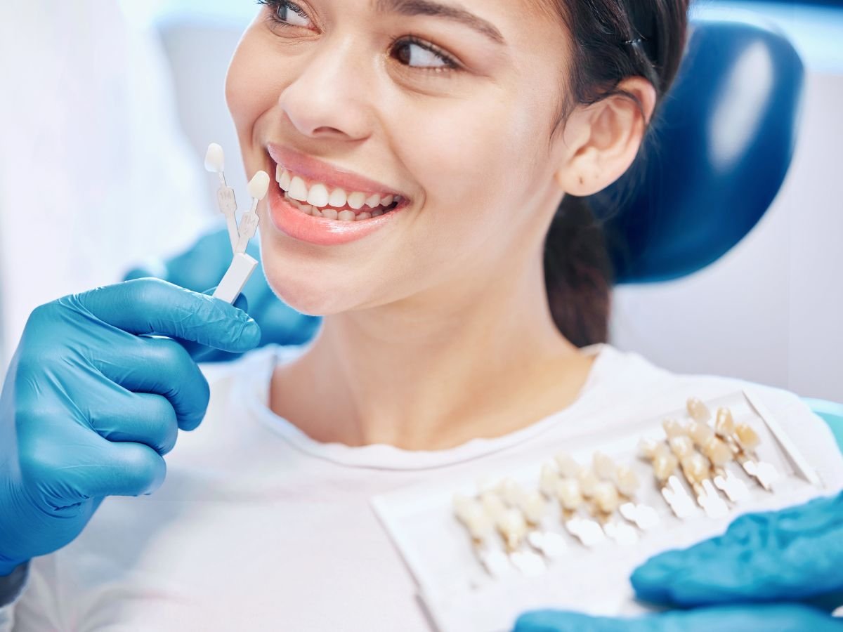 Dentist at OraCore Dental in Odenton, MD showing different types of veneers to a smiling female patient during a cosmetic dental consultation